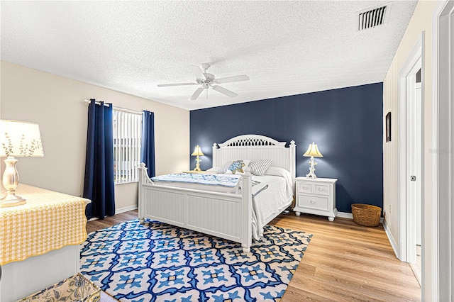 bedroom with ceiling fan, hardwood / wood-style floors, and a textured ceiling