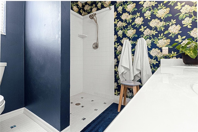 bathroom with tile patterned flooring, toilet, and a tile shower