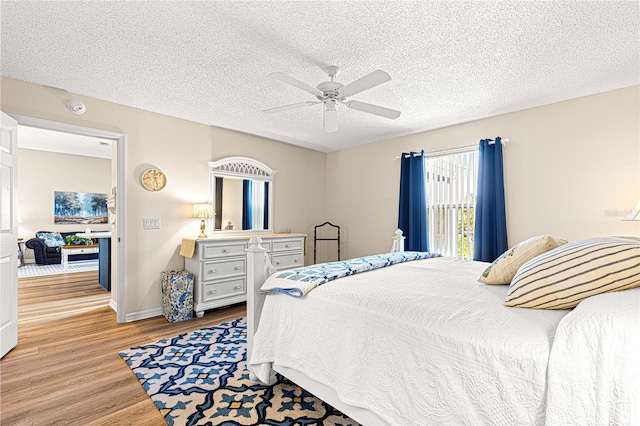 bedroom with ceiling fan, light hardwood / wood-style floors, and a textured ceiling