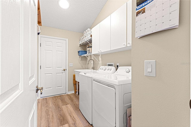 clothes washing area featuring light hardwood / wood-style flooring, cabinets, a textured ceiling, and independent washer and dryer