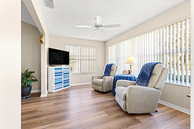 sitting room with a wealth of natural light, ceiling fan, and hardwood / wood-style flooring