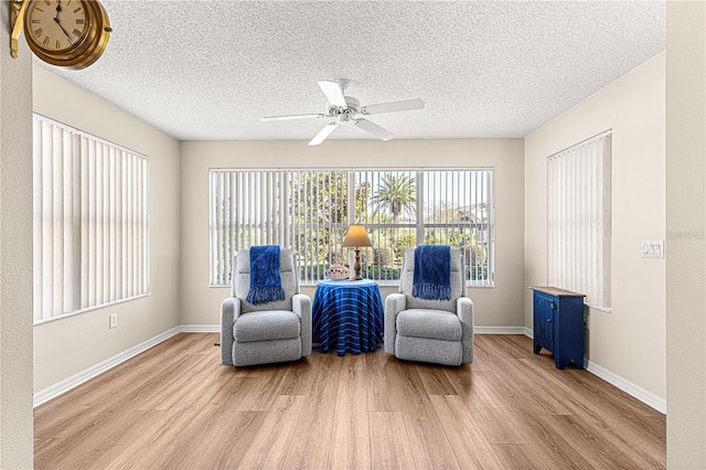 sitting room with a textured ceiling, light hardwood / wood-style flooring, and ceiling fan