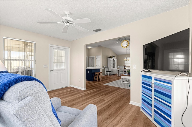 bedroom with ceiling fan, vaulted ceiling, a textured ceiling, and light hardwood / wood-style flooring