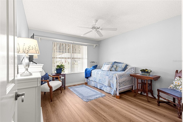 bedroom featuring ceiling fan, light wood-type flooring, and a textured ceiling