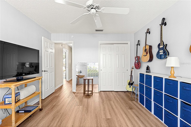 interior space featuring ceiling fan, light hardwood / wood-style flooring, and a textured ceiling