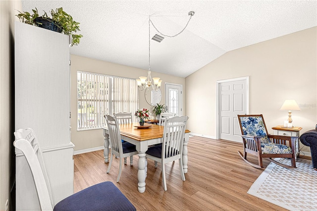 dining room featuring a textured ceiling, light hardwood / wood-style floors, an inviting chandelier, and lofted ceiling