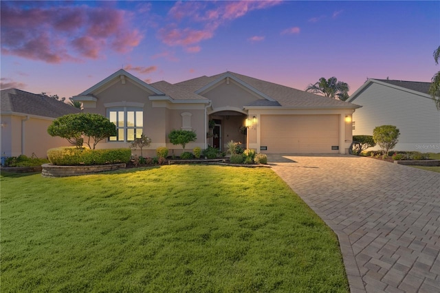 ranch-style home with a garage and a yard