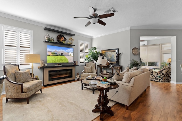 living room with a textured ceiling, wood-type flooring, crown molding, and a wealth of natural light