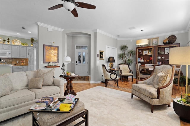 living room featuring ceiling fan, crown molding, and light hardwood / wood-style flooring