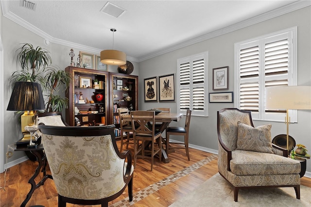 dining space with crown molding and light hardwood / wood-style floors