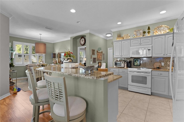 kitchen featuring white appliances, decorative light fixtures, ornamental molding, and light tile patterned flooring