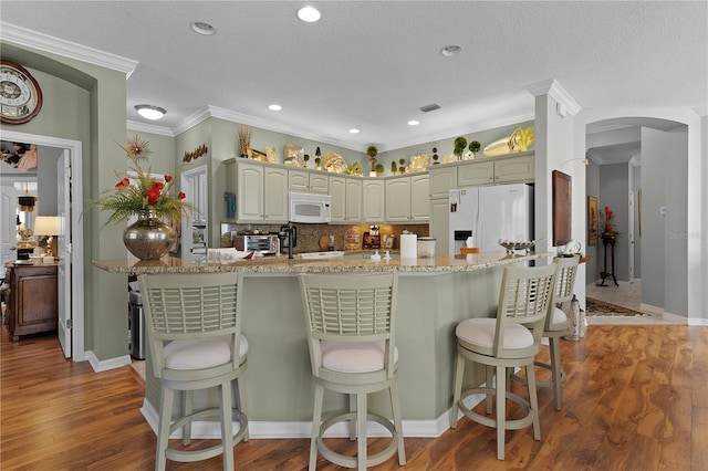 kitchen featuring wood-type flooring, white appliances, a textured ceiling, and ornamental molding