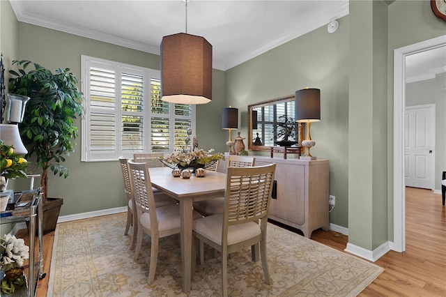 dining space with light wood-type flooring and ornamental molding