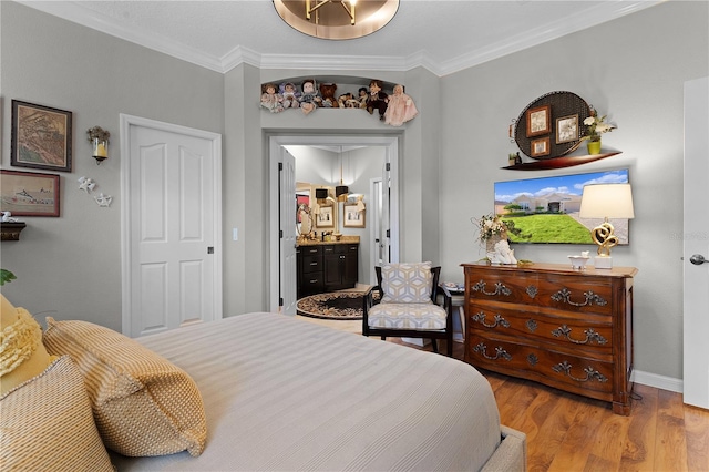 bedroom featuring light hardwood / wood-style flooring, ensuite bath, and crown molding