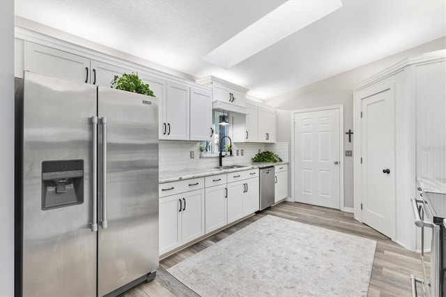 kitchen with white cabinetry, sink, light hardwood / wood-style flooring, and appliances with stainless steel finishes