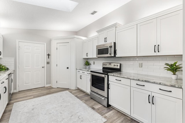 kitchen with light hardwood / wood-style floors, white cabinetry, appliances with stainless steel finishes, and tasteful backsplash