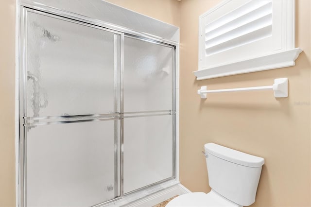 bathroom featuring a shower with shower door and toilet