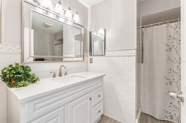 bathroom with curtained shower, hardwood / wood-style floors, vanity, and tile walls