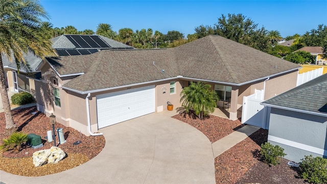 ranch-style house featuring a garage and solar panels