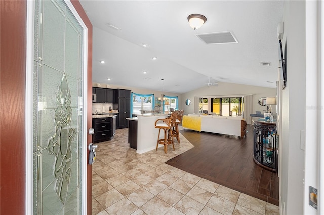 kitchen featuring a kitchen bar, light wood-type flooring, vaulted ceiling, decorative light fixtures, and a kitchen island