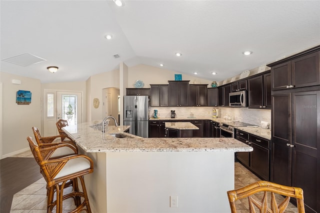 kitchen with appliances with stainless steel finishes, a large island, sink, light hardwood / wood-style floors, and lofted ceiling