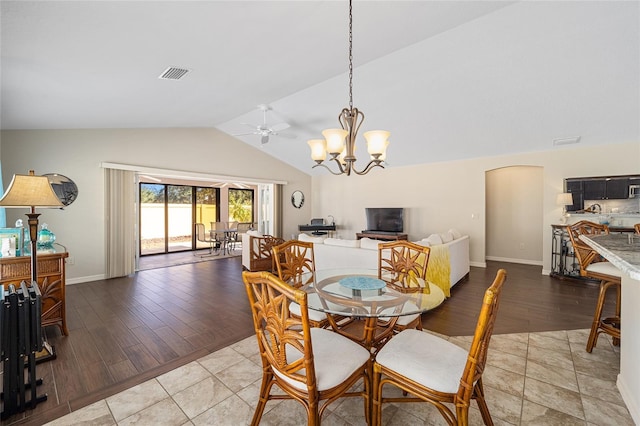 dining space featuring ceiling fan with notable chandelier, wood-type flooring, and lofted ceiling