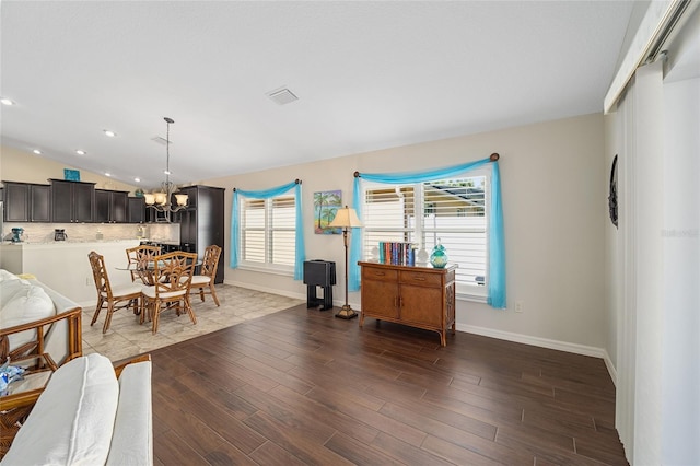 dining area featuring dark hardwood / wood-style floors, lofted ceiling, and an inviting chandelier