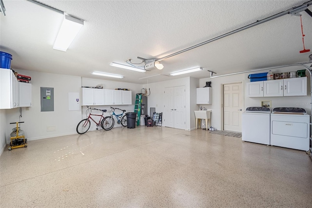 garage with electric panel, a garage door opener, washer and clothes dryer, and sink