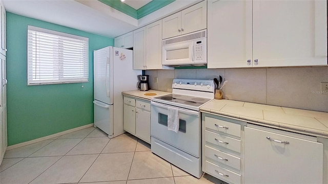 kitchen with white cabinetry, white appliances, light tile patterned floors, and tasteful backsplash