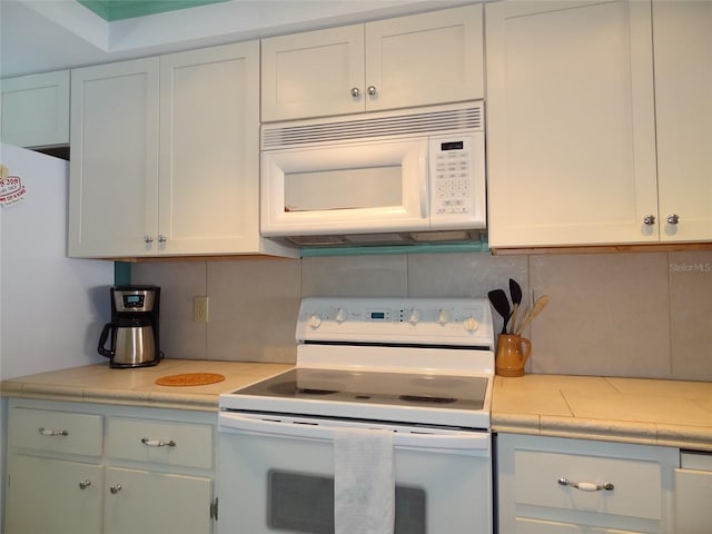 kitchen with white cabinets, decorative backsplash, and white appliances