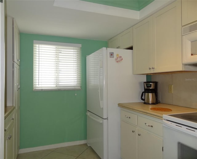 kitchen featuring light tile patterned flooring, white appliances, white cabinetry, and backsplash