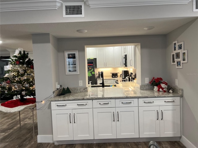 bar with white cabinets, dark hardwood / wood-style floors, light stone countertops, and sink