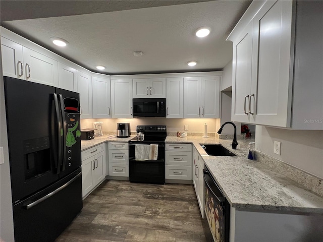 kitchen featuring white cabinets, sink, light stone counters, and black appliances