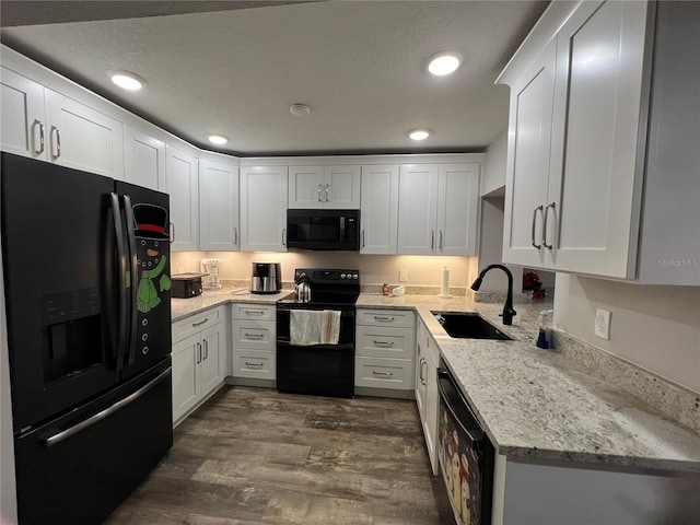 kitchen featuring light stone countertops, a textured ceiling, sink, black appliances, and white cabinetry