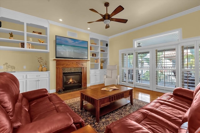 living room with ceiling fan, a high end fireplace, light hardwood / wood-style floors, and ornamental molding