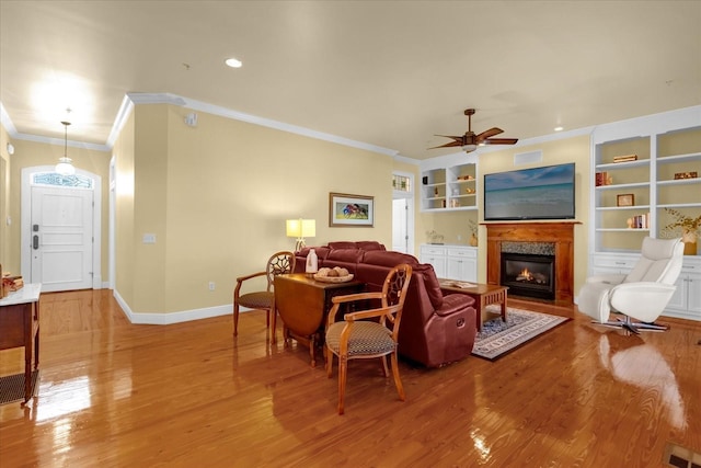 living room with ceiling fan, light wood-type flooring, and crown molding