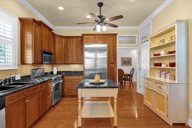 kitchen featuring a center island, high end appliances, crown molding, sink, and light hardwood / wood-style flooring