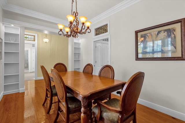 dining room with light hardwood / wood-style flooring, a notable chandelier, and crown molding