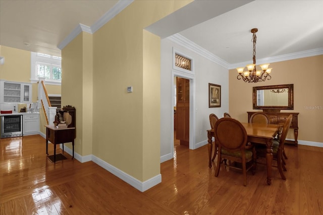 dining space featuring hardwood / wood-style flooring, wine cooler, crown molding, and a notable chandelier