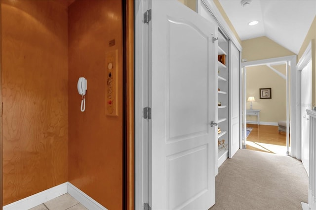 hallway with light colored carpet and vaulted ceiling