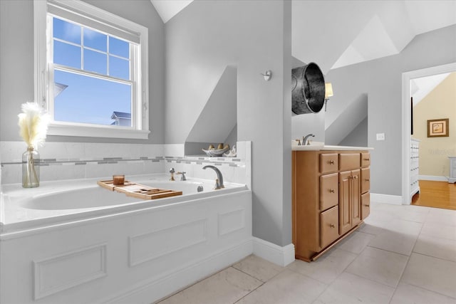 bathroom featuring tile patterned flooring, vanity, vaulted ceiling, and a tub