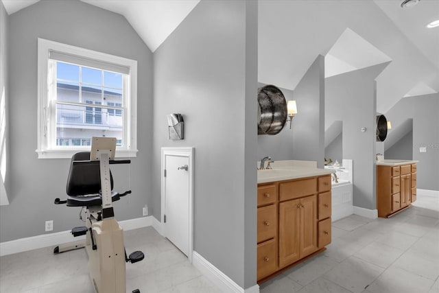 bathroom featuring a bathing tub, vanity, and lofted ceiling