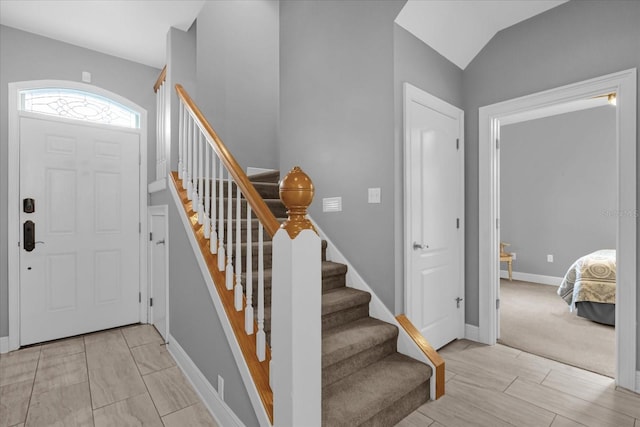 carpeted foyer entrance featuring vaulted ceiling