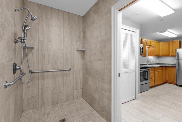 bathroom featuring tiled shower and vanity