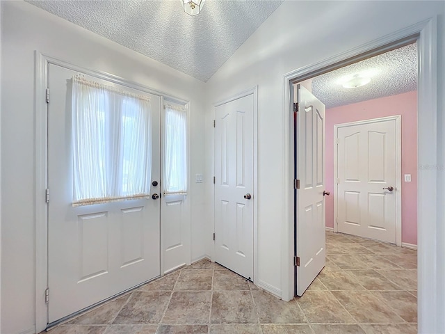 entryway featuring a textured ceiling and vaulted ceiling