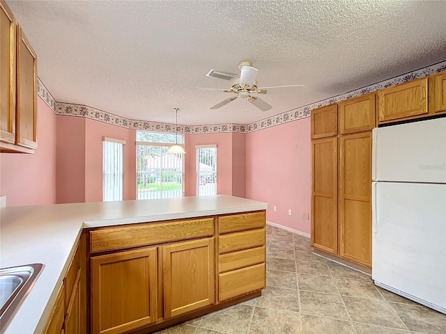 kitchen with pendant lighting, ceiling fan, a textured ceiling, white fridge, and kitchen peninsula