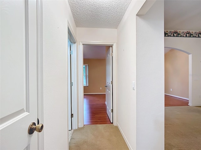 hall featuring light wood-type flooring and a textured ceiling