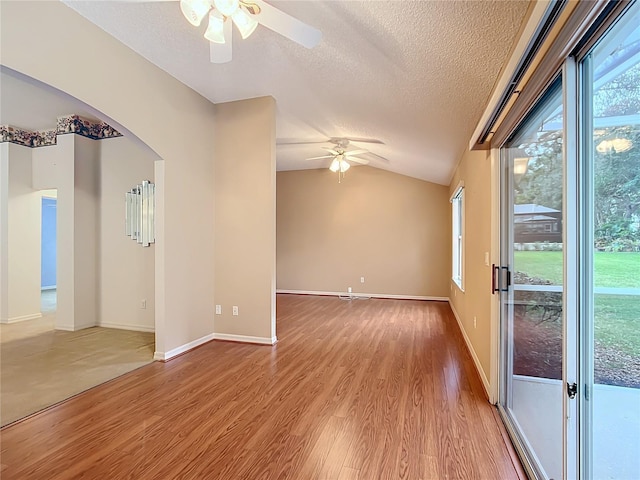 spare room featuring ceiling fan, lofted ceiling, a textured ceiling, and light hardwood / wood-style flooring