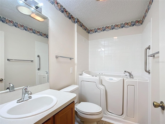 bathroom featuring a tub, vanity, a textured ceiling, and toilet