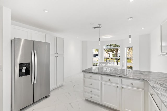 kitchen with decorative light fixtures, stainless steel fridge, light stone countertops, and white cabinetry